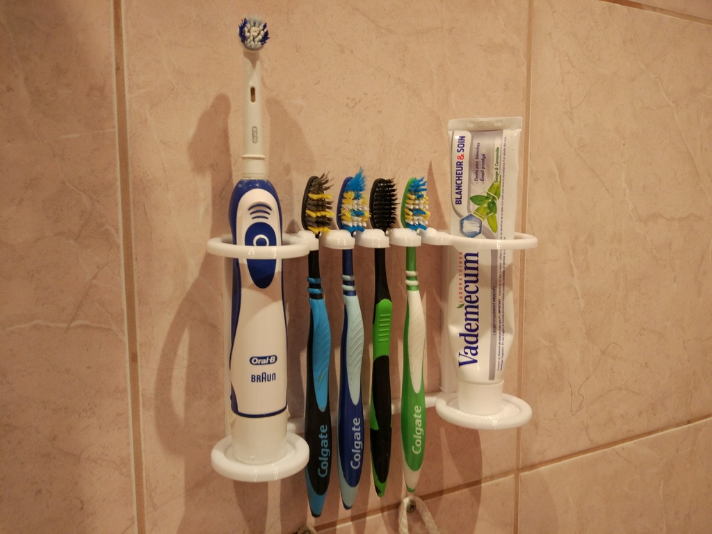 The holder on a wall for toothbrushes and paste.